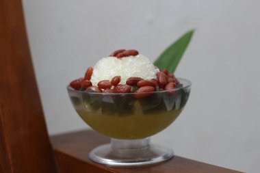 Es Kacang Merah or a cold drink made from red beans boiled with brown sugar served with coconut milk, shaved ice and covered with sweetened condensed milk chocolate and syrup. Indonesian traditional food photo concept.