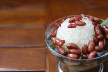 Es Kacang Merah or a cold drink made from red beans boiled with brown sugar served with coconut milk, shaved ice and covered with sweetened condensed milk chocolate and syrup. Indonesian traditional food photo concept.