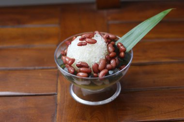 Es Kacang Merah or a cold drink made from red beans boiled with brown sugar served with coconut milk, shaved ice and covered with sweetened condensed milk chocolate and syrup. Indonesian traditional food photo concept.