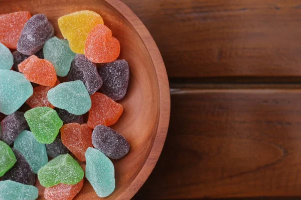 a close up of gummy candies of various colors and fruit flavors served in a wooden bowl.