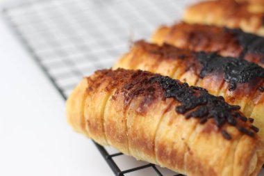 a close up of Chocolate Cheese Bolen. made of flour, cheese, chocolate, with banana filling. served on a cake rack. isolated white background.