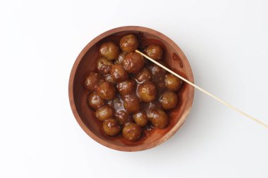 a close up of cilok. Made from tapioca flour and a delicious peanut sauce. served in wooden bowl isolated on white background.