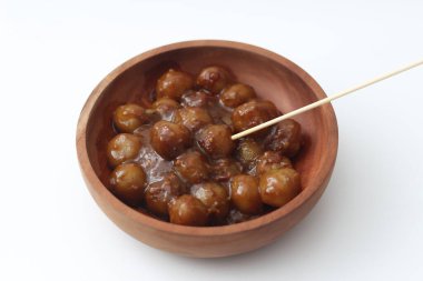 a close up of cilok. Made from tapioca flour and a delicious peanut sauce. served in wooden bowl isolated on white background.