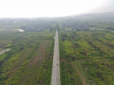 aerial view of Klapanunggal highway between trees and green open space.