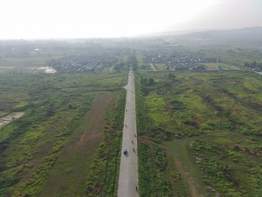 aerial view of Klapanunggal highway between trees and green open space.