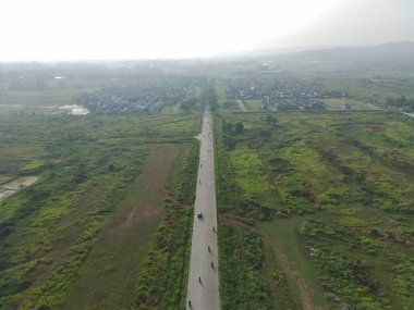 aerial view of Klapanunggal highway between trees and green open space.