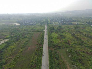 aerial view of Klapanunggal highway between trees and green open space.