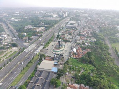 aerial view of Tugu Pancakarsa in the morning at the crossroads side by side with the toll road.