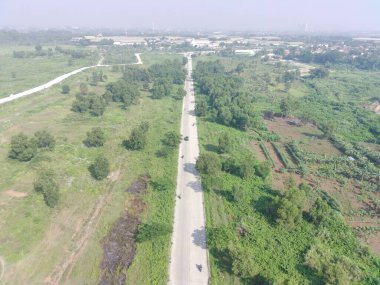 aerial view of Klapanunggal highway between trees and green open space.