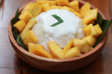 a close up of mango sticky rice with savory coconut milk gravy. Thai food concept photo.