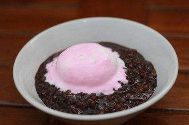 close up of a bowl of black sticky rice porridge topped with strawberry ice cream. Food concept photo.