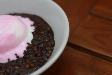 close up of a bowl of black sticky rice porridge topped with strawberry ice cream. Food concept photo.