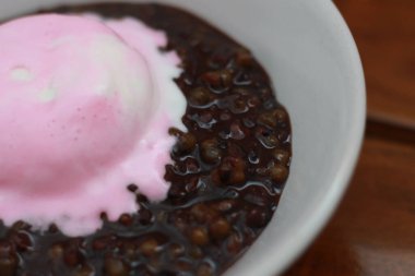 close up of a bowl of black sticky rice porridge topped with strawberry ice cream. Food concept photo.