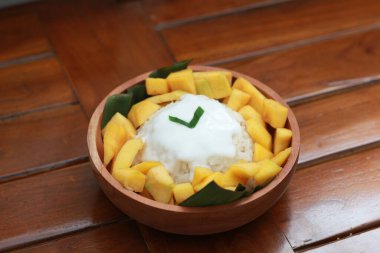 a close up of mango sticky rice with savory coconut milk gravy. Thai food concept photo.