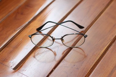 a close up of eyeglasses with black frames isolated natural patterned wooden background.