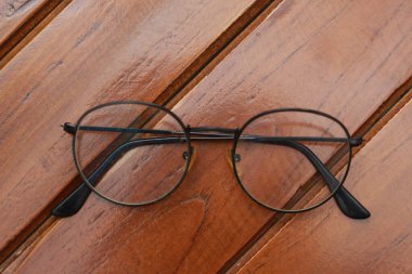 a close up of eyeglasses with black frames isolated natural patterned wooden background.