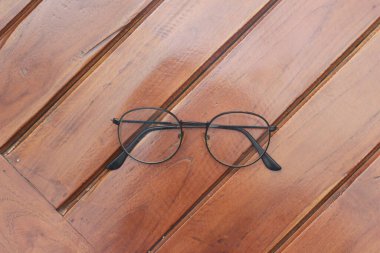 a close up of eyeglasses with black frames isolated natural patterned wooden background.