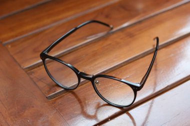 a close up of eyeglasses with black frames isolated natural patterned wooden background.