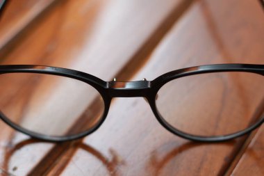 a close up of eyeglasses with black frames isolated natural patterned wooden background.