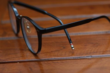 a close up of eyeglasses with black frames isolated natural patterned wooden background.