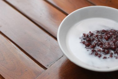 a close up of a bowl of black sticky rice porridge with coconut milk ready to eat. Indonesian traditional food concept.
