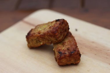 a close up of fried tempeh on a wooden cutting board. Indonesian traditional food concept.