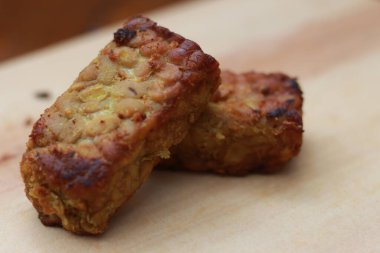 a close up of fried tempeh on a wooden cutting board. Indonesian traditional food concept.