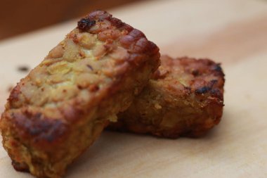 a close up of fried tempeh on a wooden cutting board. Indonesian traditional food concept.