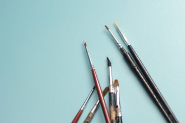 a close up of a painting brush isolated on a blue background. concept photo art.