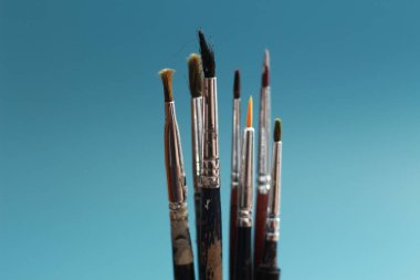 a close up of a painting brush isolated on a blue background. concept photo art.