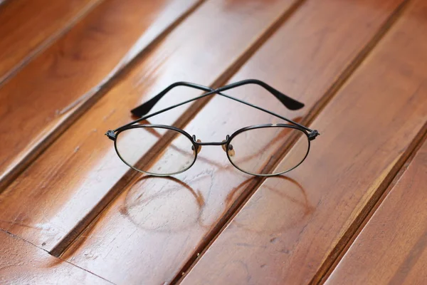 a close up of eyeglasses with black frames isolated natural patterned wooden background.