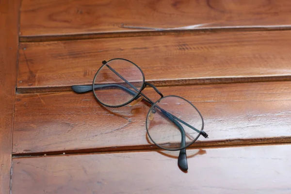 a close up of eyeglasses with black frames isolated natural patterned wooden background.