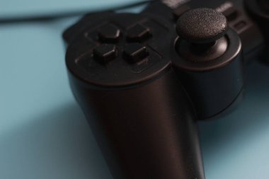 a close up of a joystick in black isolated on a blue background. online game tool photo concept.