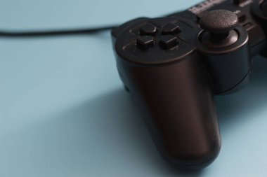 a close up of a joystick in black isolated on a blue background. online game tool photo concept.