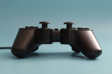 a close up of a joystick in black isolated on a blue background. online game tool photo concept.