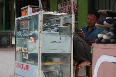 a watch repairman was waiting for a customer at his little stand by the roadside. a unique profession from Indonesia.