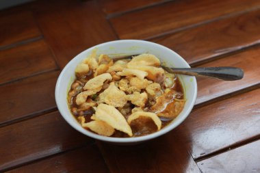 a close up of a ready-to-serve bowl of chicken porridge with a natural patterned wooden background. Indonesian food concept.