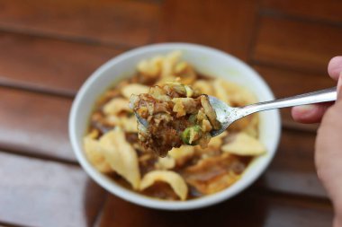 a close up of a ready-to-serve bowl of chicken porridge with a natural patterned wooden background. Indonesian food concept.