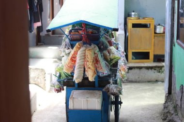 a mobile vegetable seller with a cart that was stopped in the middle of the village. a unique profession from Indonesia.