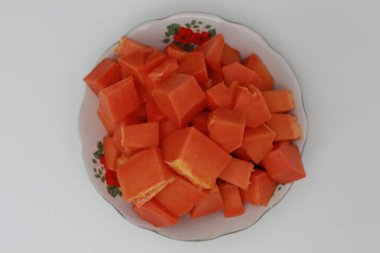 Beyaz arka planda izole edilmiş beyaz bir tabakta servis edilen Papaya dilimleri. Vücut sindirimi için sağlıklı besin kavramı.