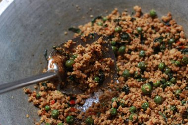 a close up of a side dish with stir-fried leunca and oncom that have been cooked on a frying pan. Indonesian traditional food photo concept.