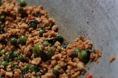 a close up of a side dish with stir-fried leunca and oncom that have been cooked on a frying pan. Indonesian traditional food photo concept.