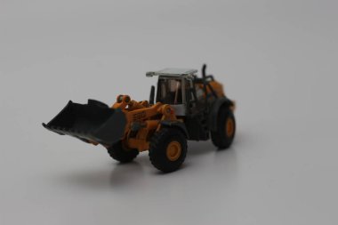 a close up of miniature orange wheel loader toy isolated on white background. concept photo of heavy equipment miniature toy.