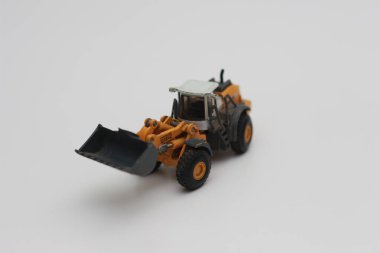 a close up of miniature orange wheel loader toy isolated on white background. concept photo of heavy equipment miniature toy.