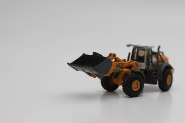 a close up of miniature orange wheel loader toy isolated on white background. concept photo of heavy equipment miniature toy.