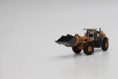 a close up of miniature orange wheel loader toy isolated on white background. concept photo of heavy equipment miniature toy.