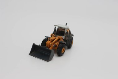 a close up of miniature orange wheel loader toy isolated on white background. concept photo of heavy equipment miniature toy.