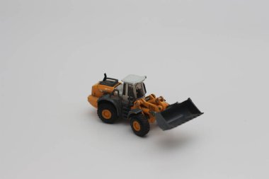 a close up of miniature orange wheel loader toy isolated on white background. concept photo of heavy equipment miniature toy.