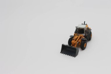 a close up of miniature orange wheel loader toy isolated on white background. concept photo of heavy equipment miniature toy.