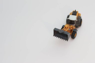 a close up of miniature orange wheel loader toy isolated on white background. concept photo of heavy equipment miniature toy.
